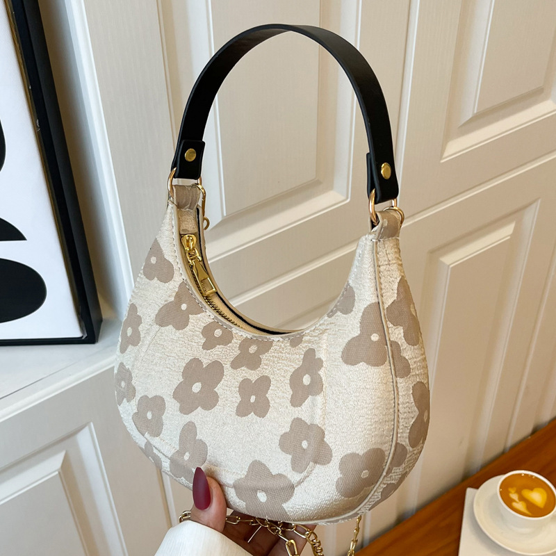 close up of a Beige floral jacquard crescent shoulder bag with black strap