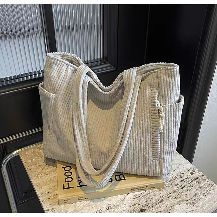 Women's beige corduroy tote bag with two side pockets and one zipper pocket in front.