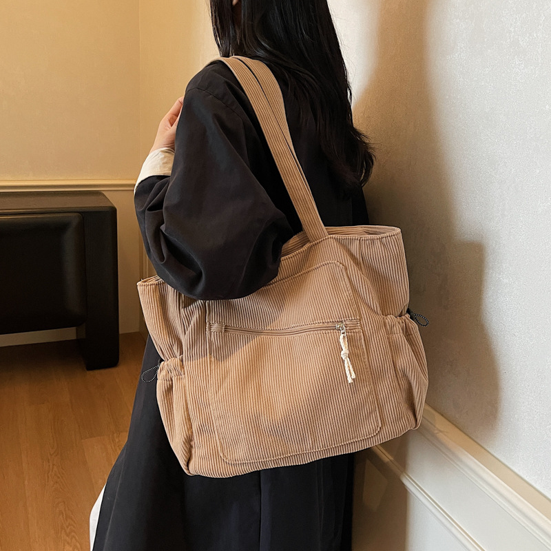 Women carrying a kakhi corduroy tote bag with zipper and slouchy pockets on her shoulder