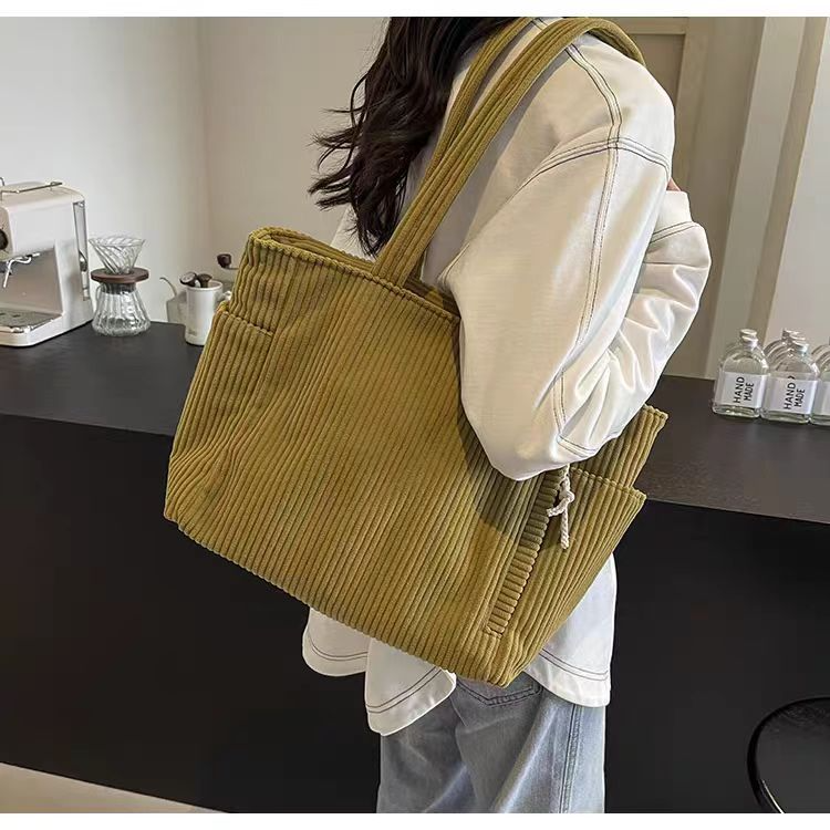 Women carrying a ginger yellow corduroy tote bag with side pockets on her shoulder