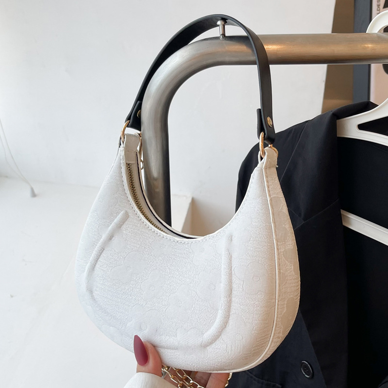 White floral jacquard crescent shoulder bag with black strap and gold tone hardware