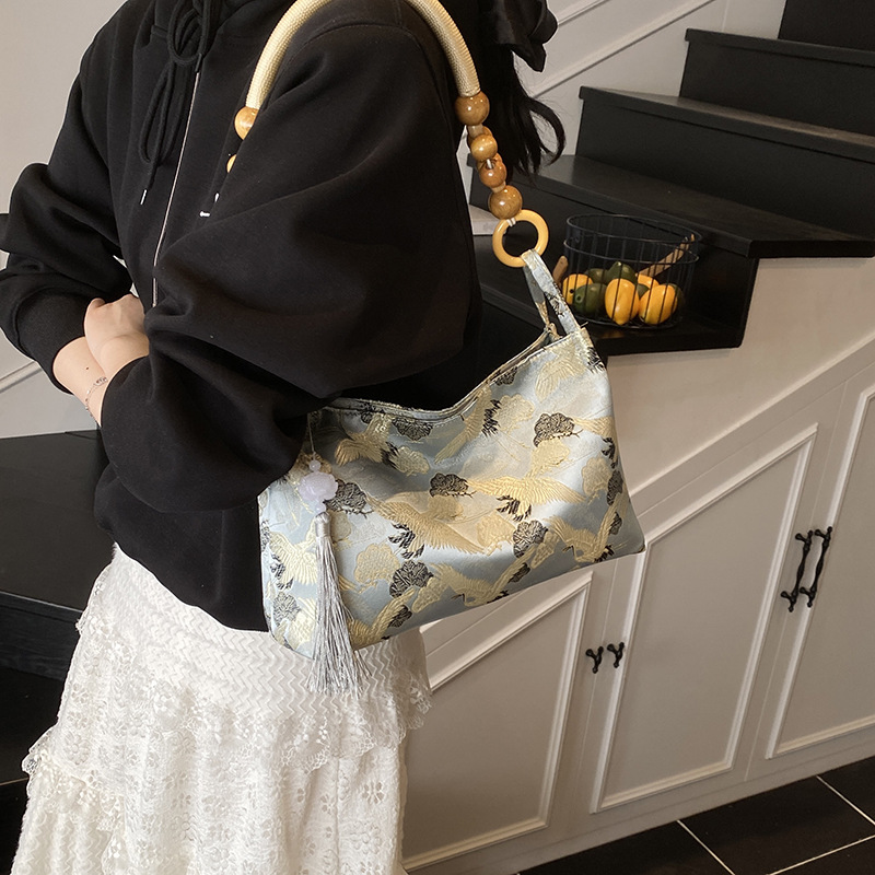 Woman carrying a Crane patthern blue jacquard  with beaded handle and tassel shoulder bag on her shoulder
