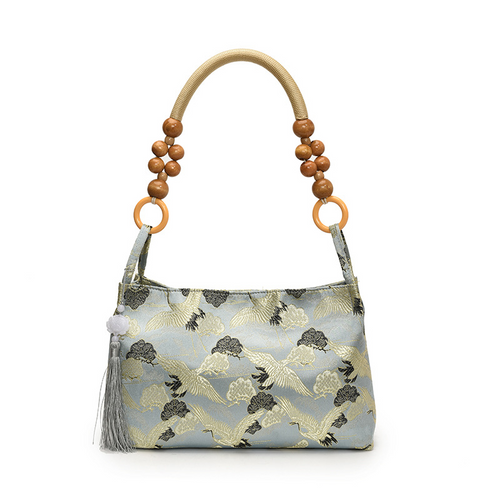 Blue pillow-style shoulder bag with flying crane pattern in jacquard and beaded handle and tassel
