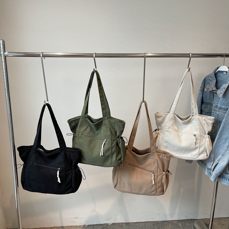 Women's green,kakhy,black, beige corduroy tote bag with zipper and side slouchy pockets hanging on a rack